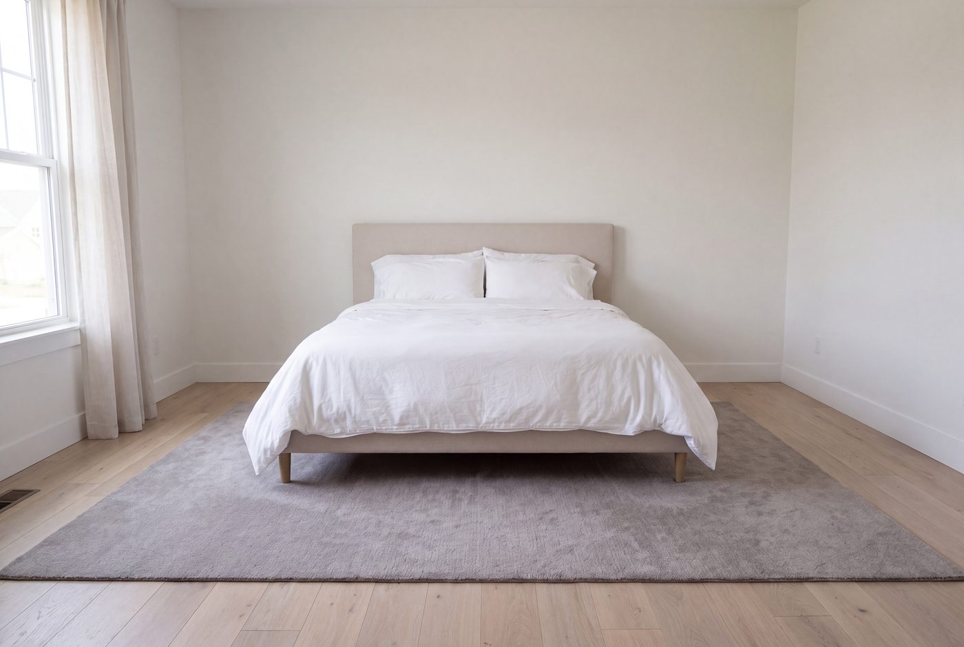A bedroom with a rug running under the lower two thirds of the bed