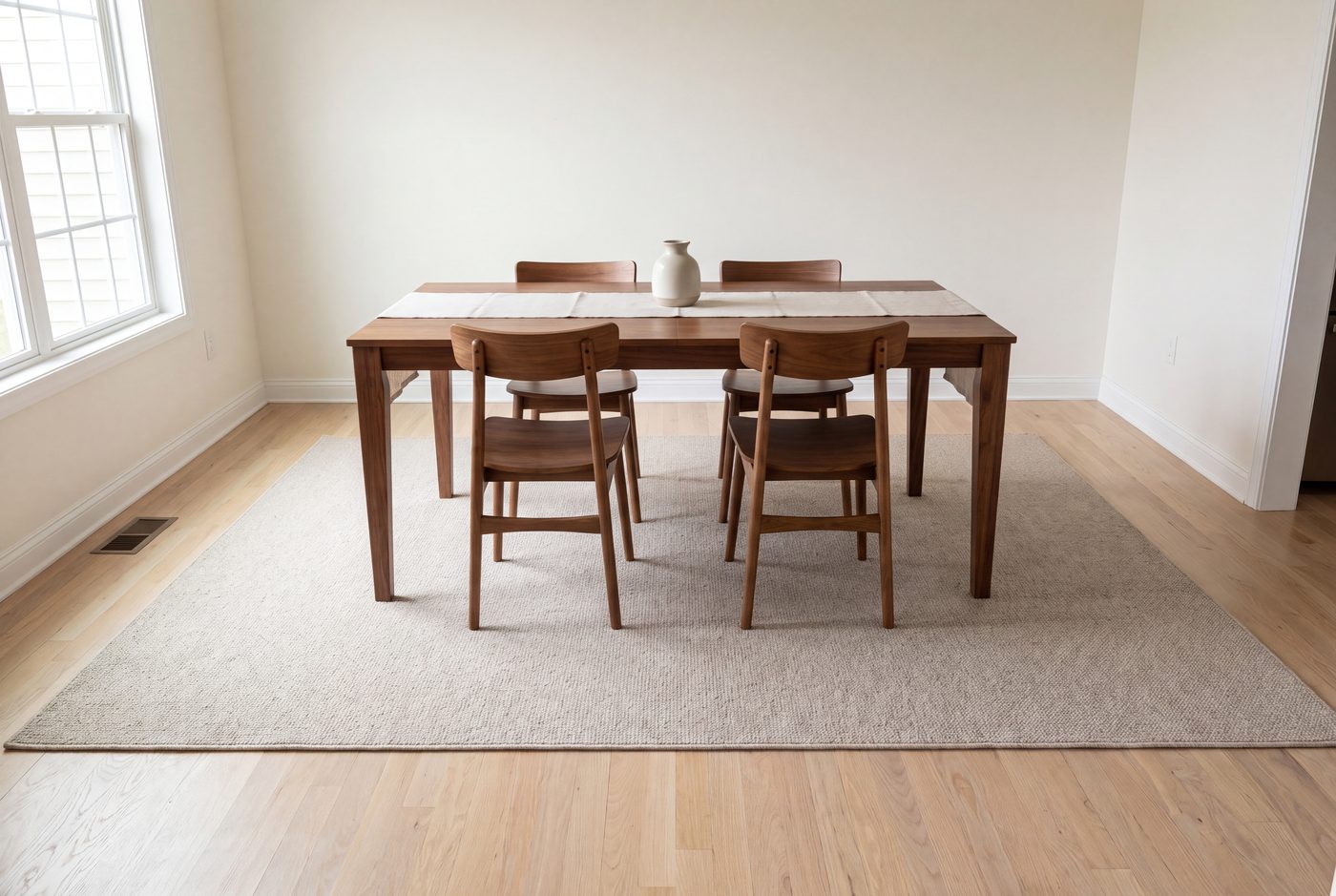 A dining table on a rug wide enough that the pulled-out chairs stay on it